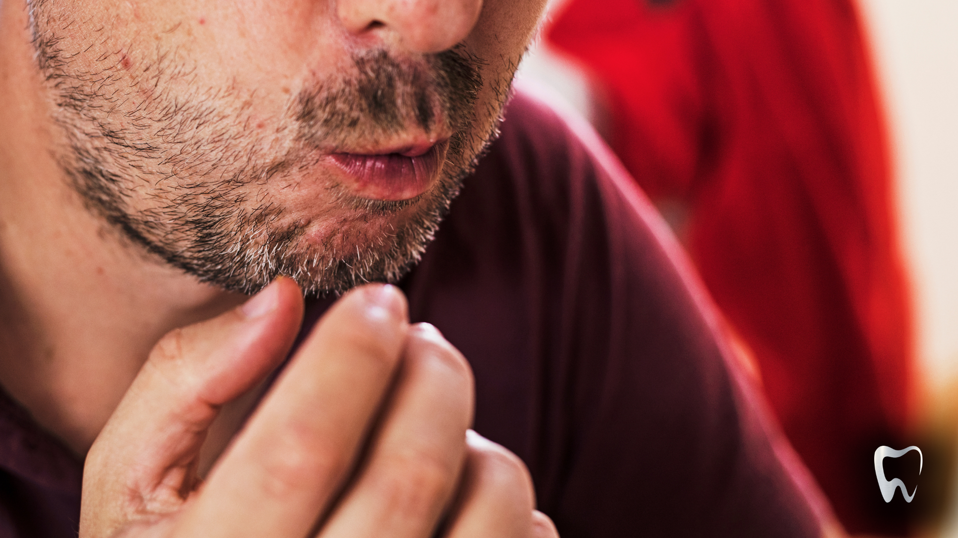 A man with a beard is holding his hands to his mouth.