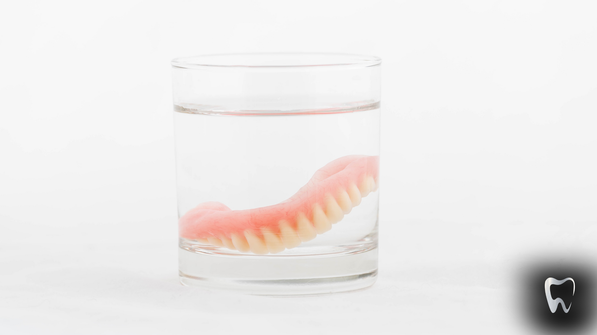 A denture is floating in a glass of water.