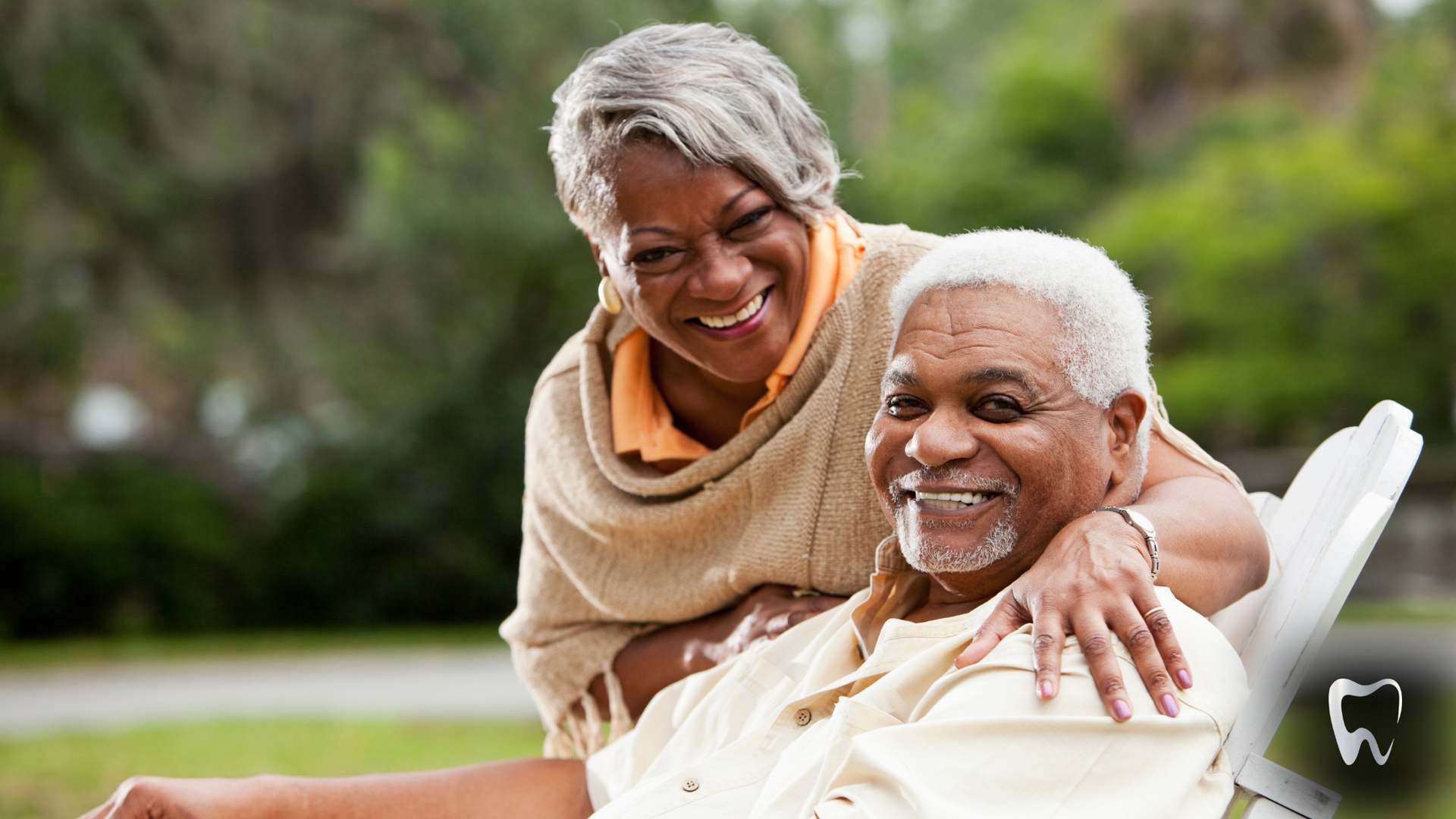 A woman is standing next to an older man in a wheelchair.