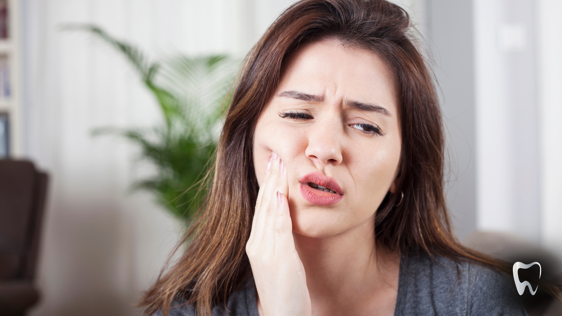 Woman holding cheek, showing signs of tooth pain.