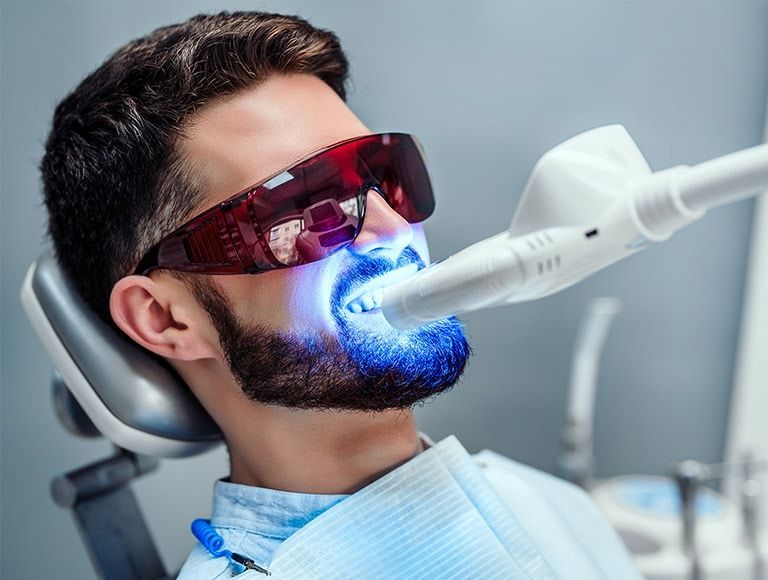 A man is getting his teeth whitened at the dentist.