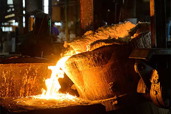 Molten metal is being poured into a ladle in a factory.