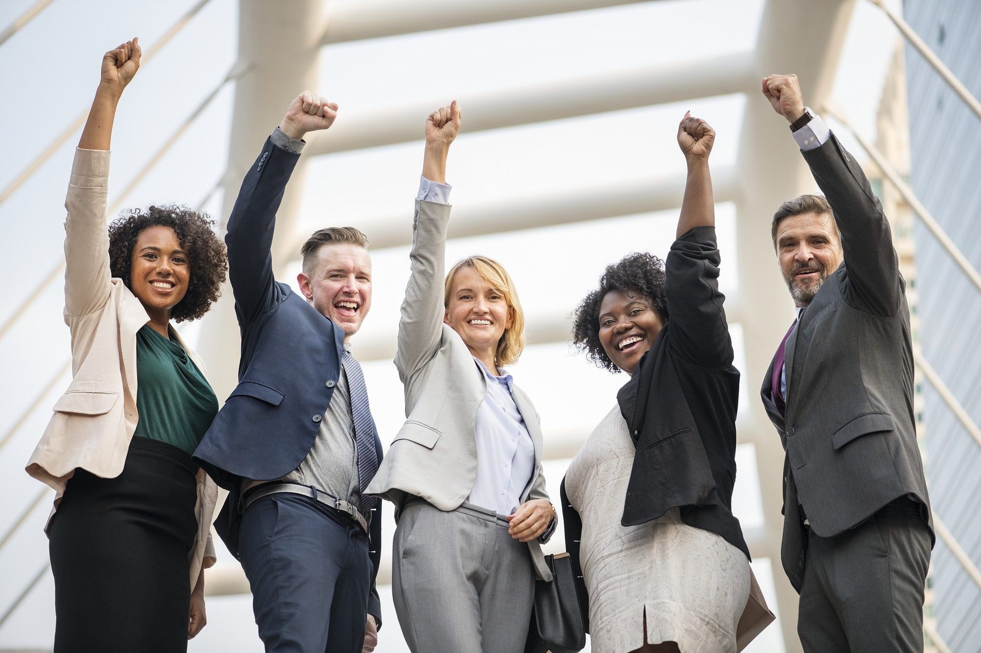 A group of business people are raising their fists in the air.