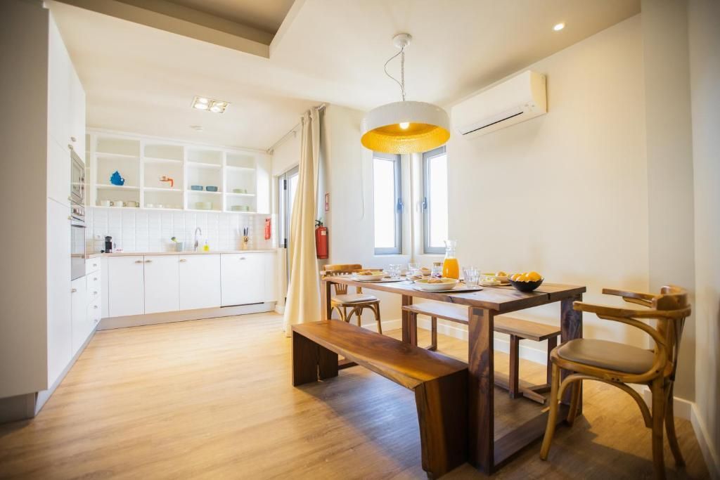 Salle à manger lumineuse avec table en bois, banc, chaises, placards blancs et suspension jaune