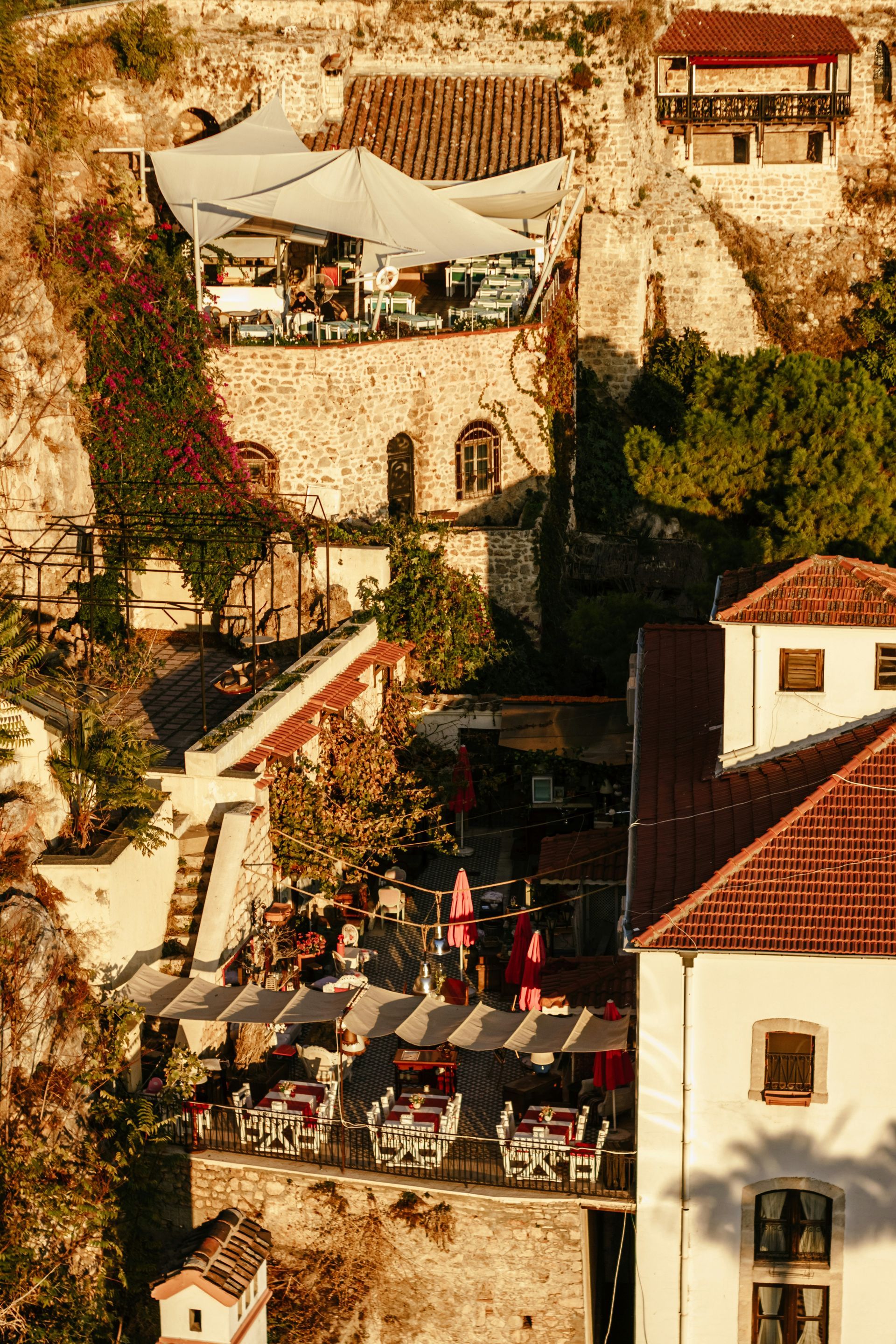 Terrasses de restaurants à flanc de falaise, avec tables, parasols et clients. 