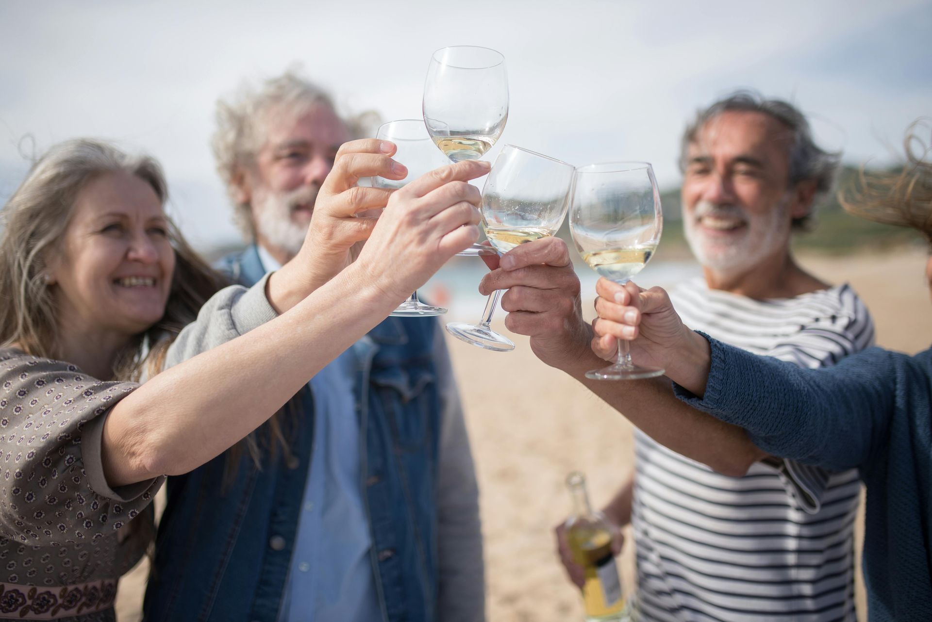 Groupe de personnes trinquant avec des verres de vin sur une plage