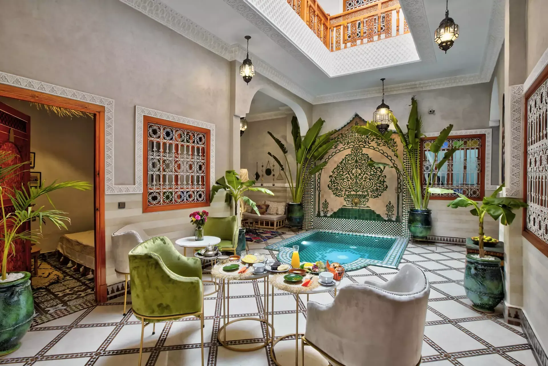 Élégant salon de cour avec une petite piscine, des sièges verts, des plantes en pot et un sol carrelé à motifs