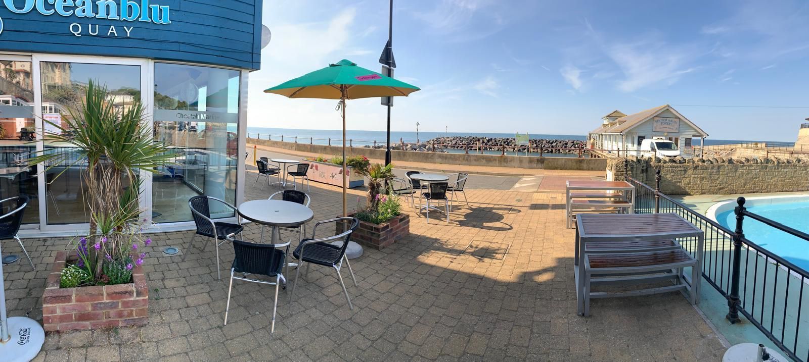 Besty & Spinky's with tables , chairs , umbrellas and a view over the sea