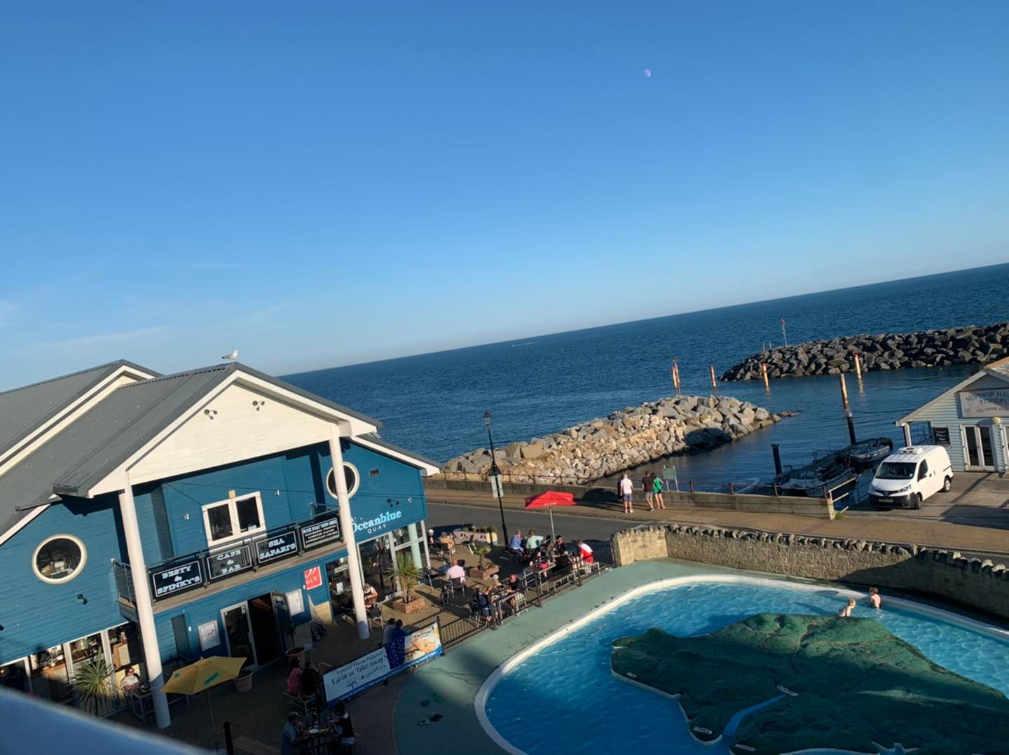 An aerial view of a building next to a swimming pool overlooking the ocean.