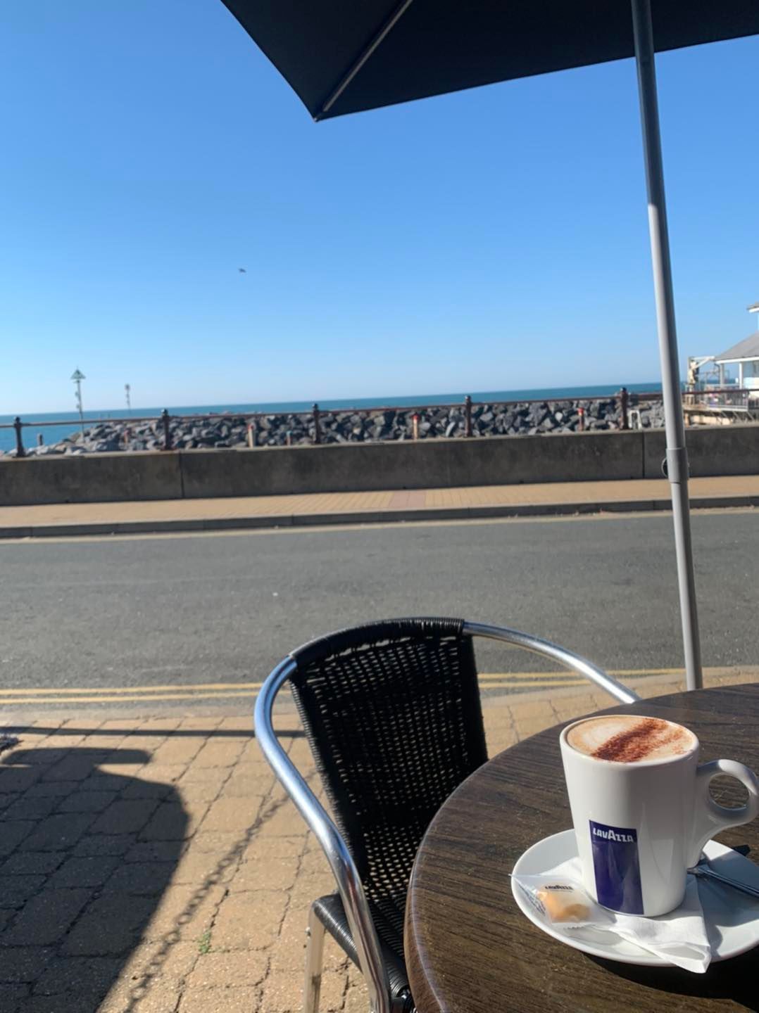 A cup of lavazza coffee sits on a table outside