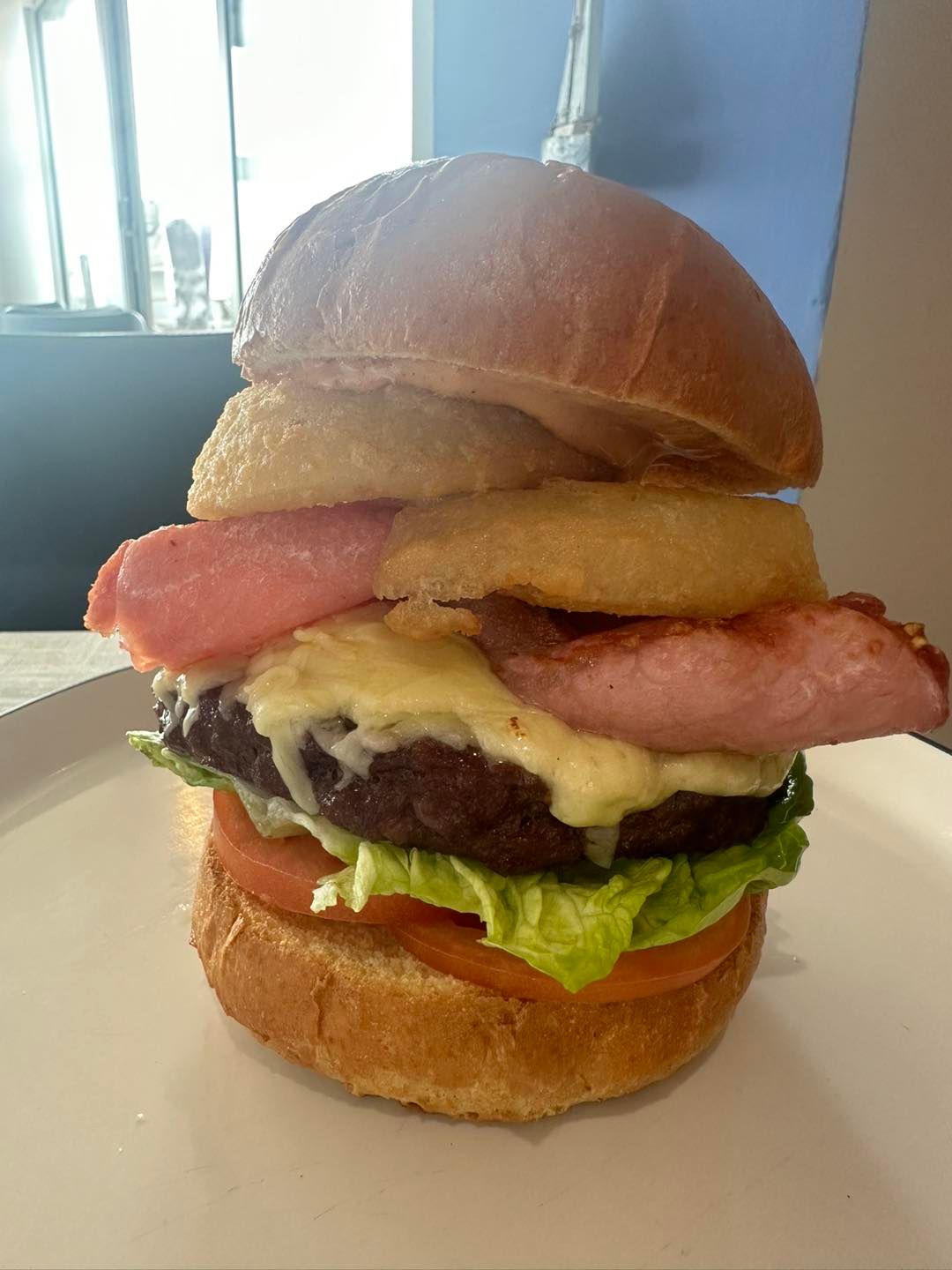 A close up of a hamburger on a white plate.