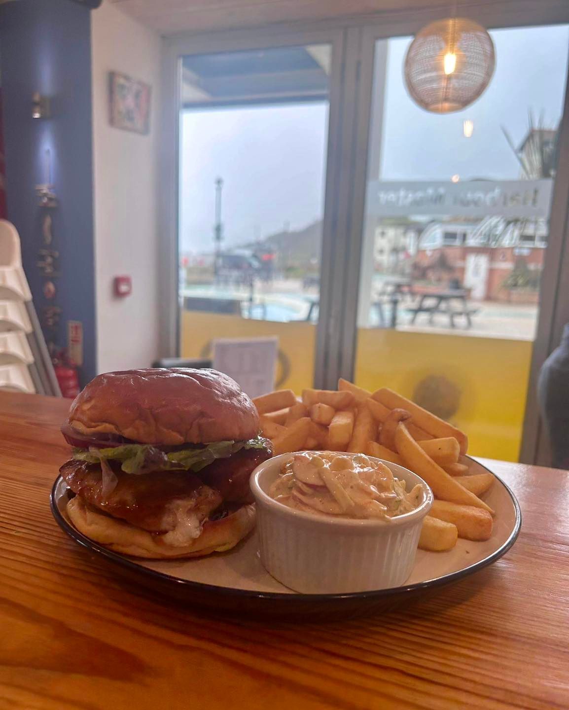 A hamburger and french fries on a plate on a wooden table.