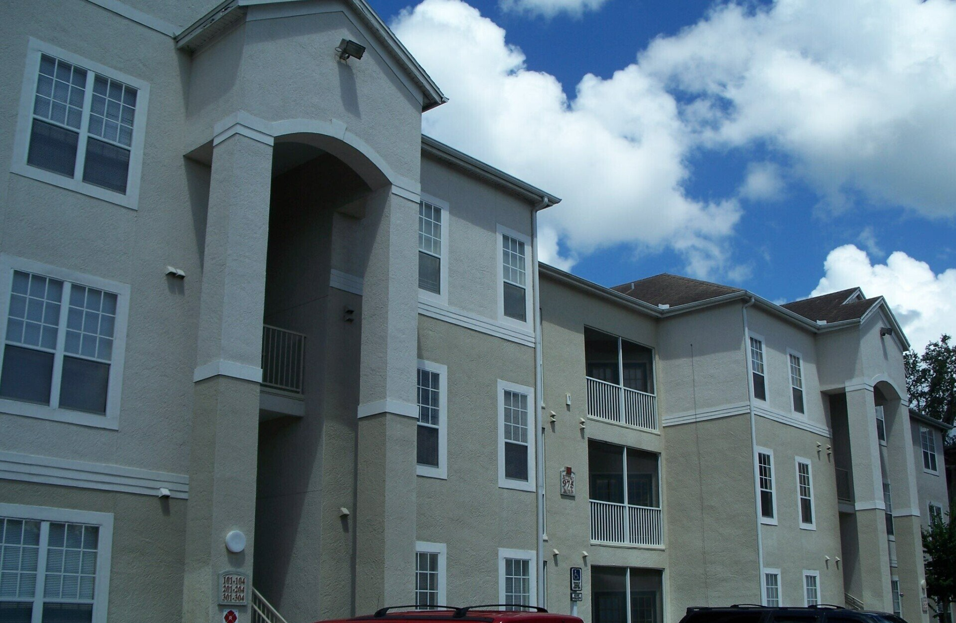 A large apartment building with a red suv parked in front of it