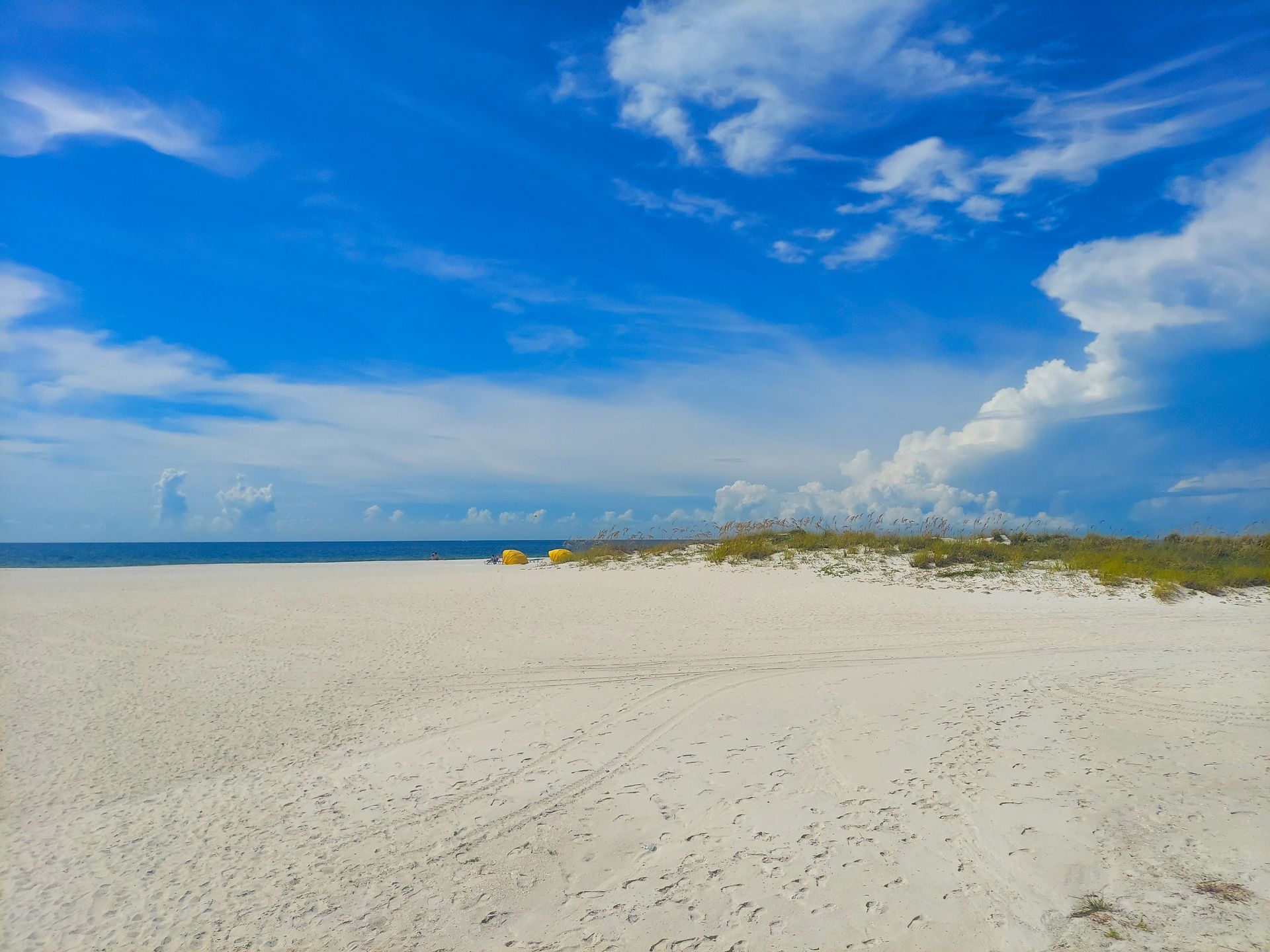 A beach with a blue sky and white clouds