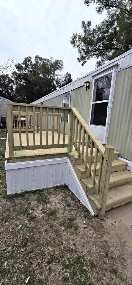 Mobile home entrance with wooden accessibility ramp and steps on a dirt yard