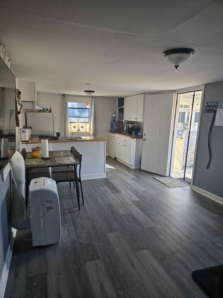Bright kitchen and dining area with gray floors, white cabinets, and sliding glass door.