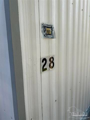 White corrugated wall with unit number 28 and a small warning sign above it