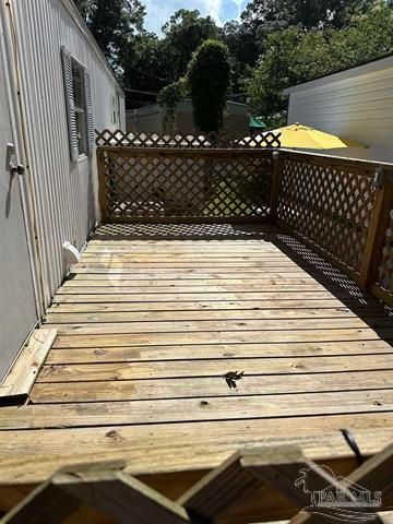 Small wooden deck with lattice railing beside a house, in bright daylight.