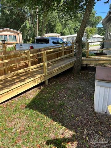 Wooden ramp with railings beside a mobile home in a shaded yard