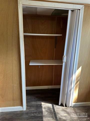 Open closet with wood paneling, white shelves, and a partially open folding door.