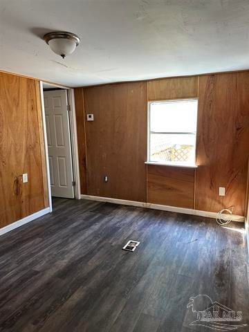 Empty wood-paneled room with gray floor, white door, and one window.