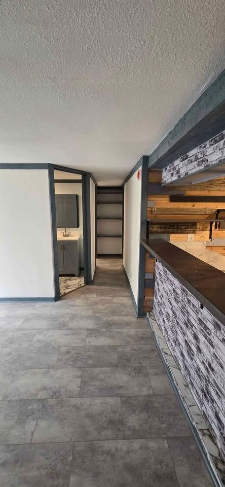 Modern kitchen interior with gray tile floor, white cabinets, and a stone-accented breakfast bar
