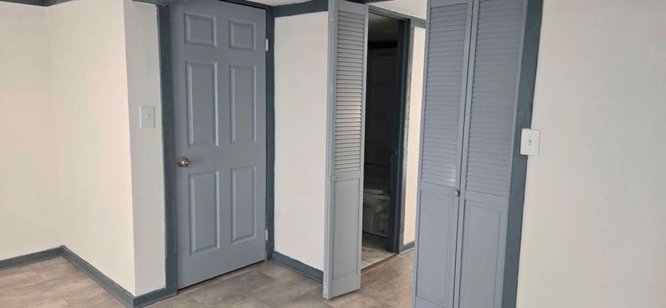 Closet doors and a small hall with gray walls, white trim, and beige carpet in an empty room