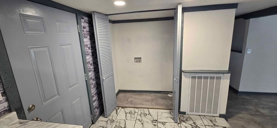 Interior hallway with gray doors, a white wall, and black-and-white tiled floor