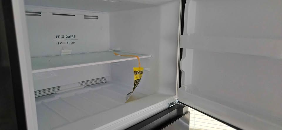 Empty refrigerator interior with a built-in ice maker and shelf.