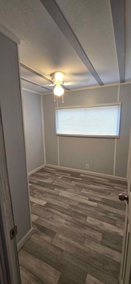 Empty gray bedroom with ceiling fan, window blinds, and wood-look flooring