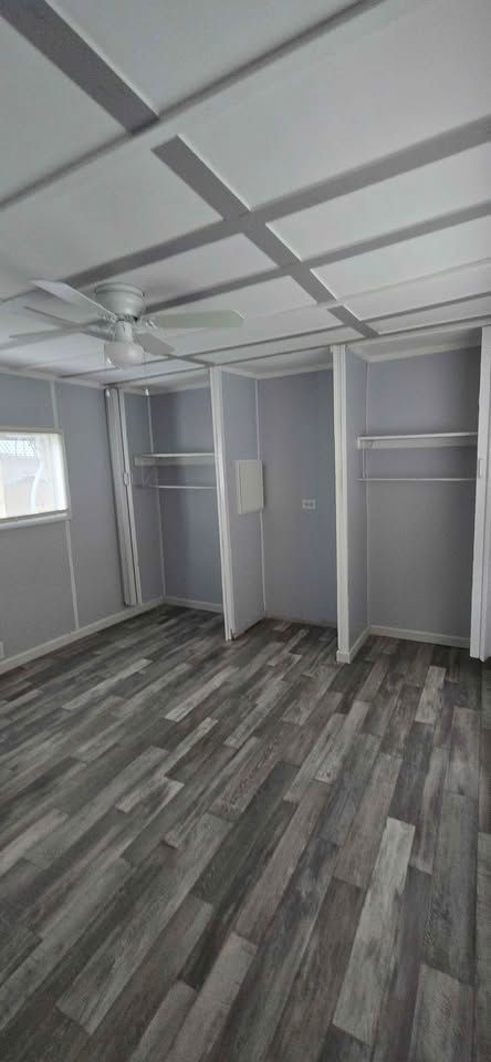 Empty gray room with patterned dark flooring, white ceiling panels, and built-in shelves.