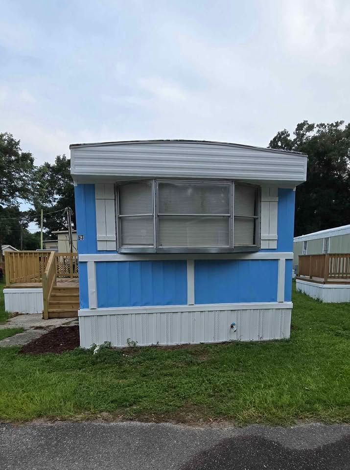 Blue and white mobile home with closed windows on a grassy lot