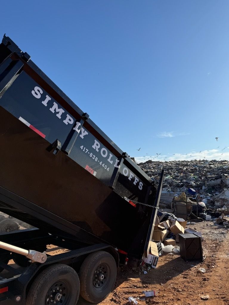 Dump truck unloading debris at a landfill under a clear blue sky.