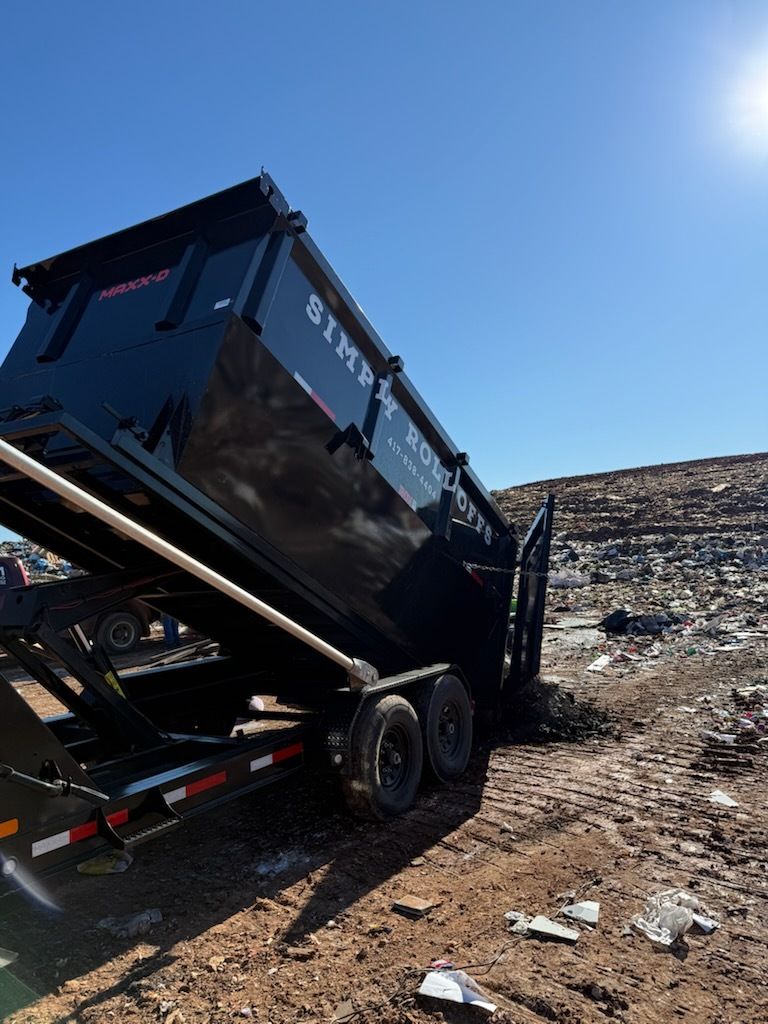 Black dump truck raised on a dirt hillside under a clear blue sky