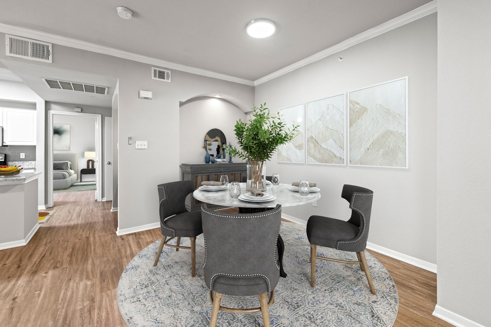 Modern dining room with round table, gray chairs, and wall art on light gray walls and wood floors