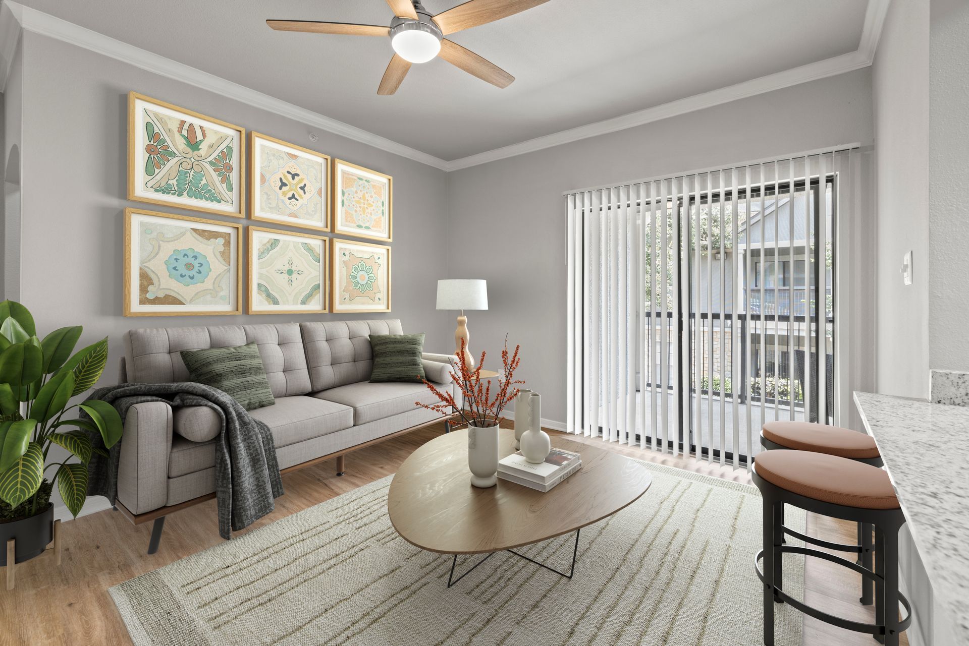 Bright living room with gray sofa, round coffee table, wall art, ceiling fan, and sliding glass doors.
