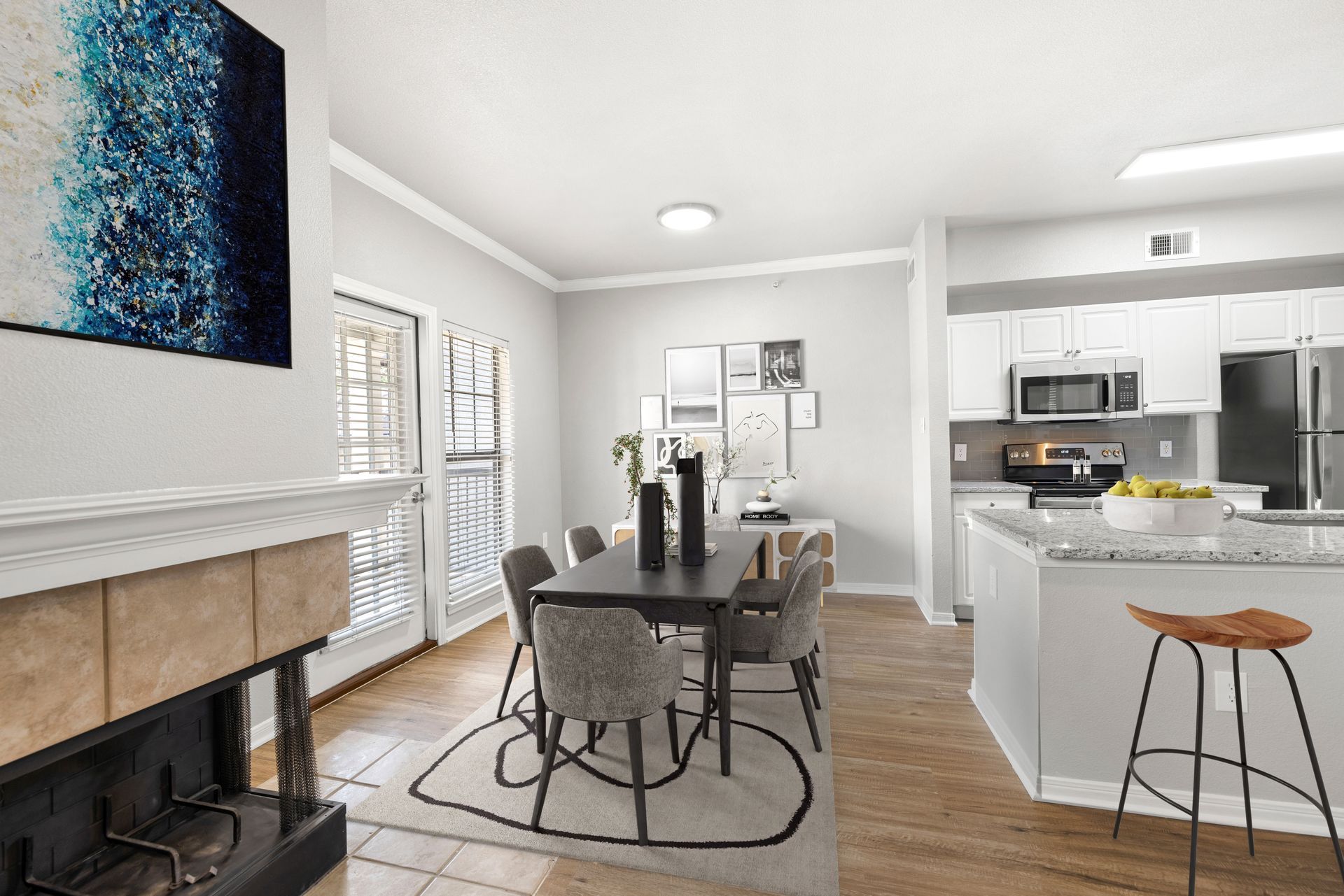 Bright open dining area with table, fireplace, and kitchen with bar stools