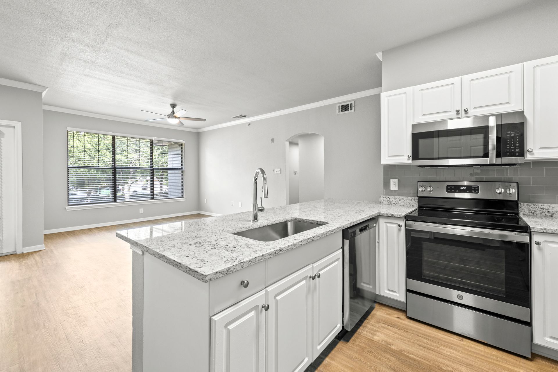 Bright modern kitchen with white cabinets, granite island, and stainless steel appliances