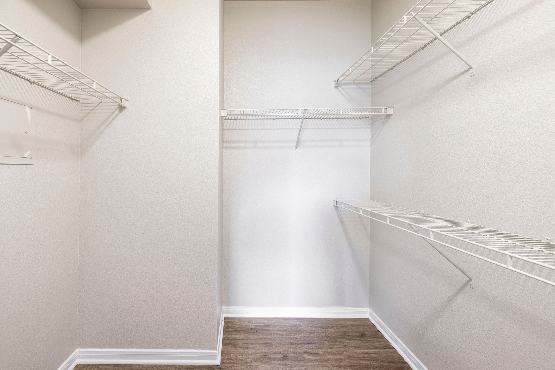 Empty walk-in closet with white wire shelving and wood flooring
