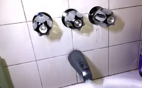 GTZ Plumbing Service LLC - A bathroom with a bathtub and three faucets on the wall.