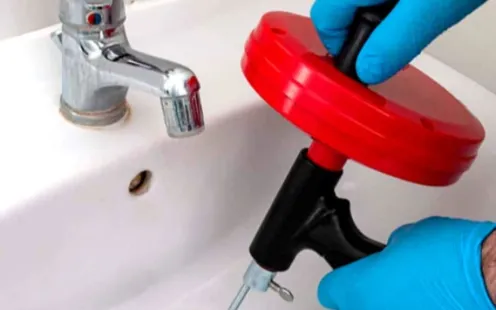 GTZ Plumbing Service LLC - A person is using a drain snake to unblock a sink.