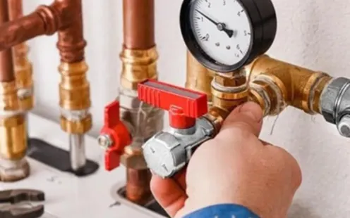 GTZ Plumbing Service LLC - A person is working on a pipe with a gauge on it.