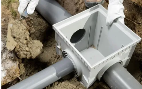 GTZ Plumbing Service LLC - A person is working on a drainage system in the dirt.