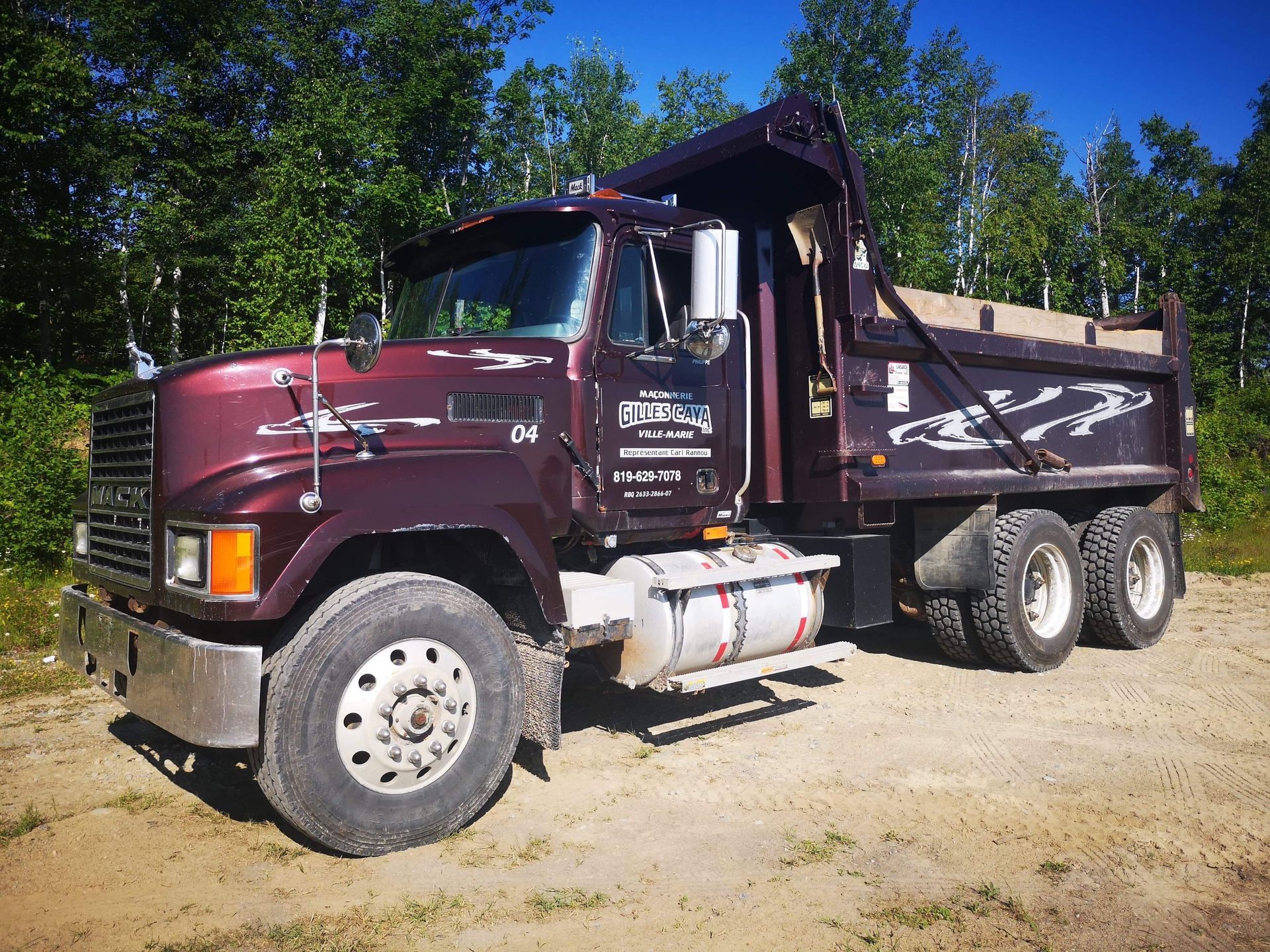 Un camion-benne Mack est garé dans un terrain sale