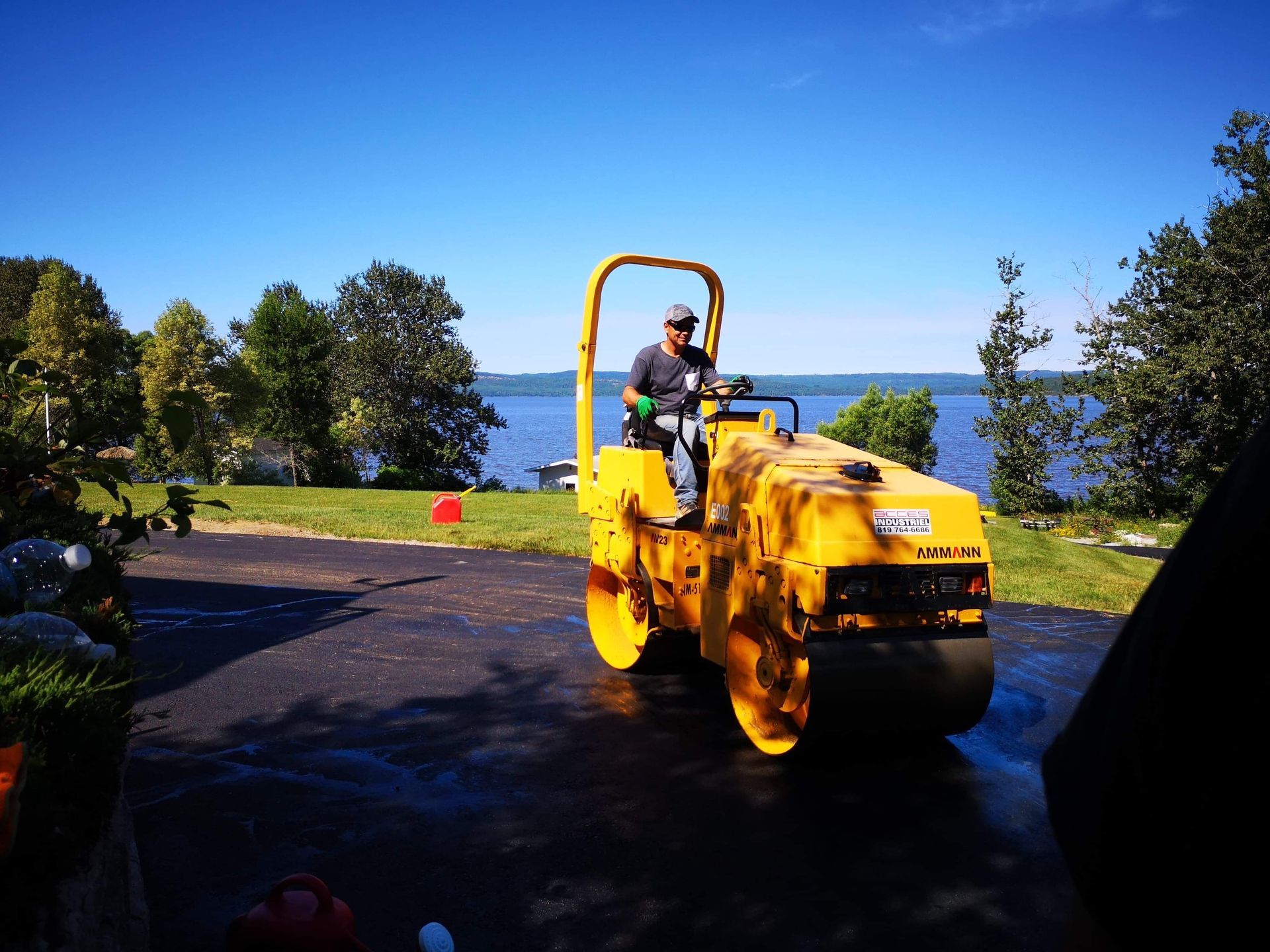 Un homme conduit un rouleau jaune sur une route près d un lac