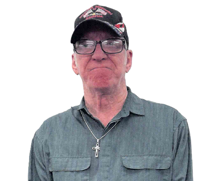 Man in glasses and cap, wearing a button-down shirt and cross necklace, with a neutral expression.