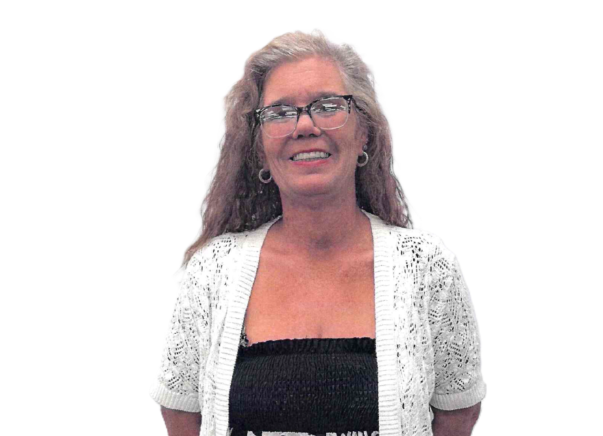 Woman in glasses and white cardigan smiles, looking at the camera.