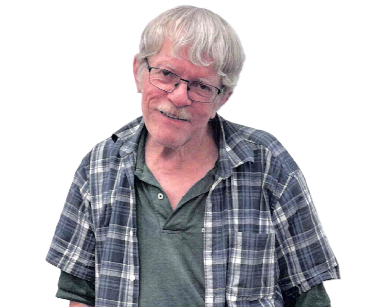 Man with glasses, gray hair and mustache, wearing plaid shirt, smiling slightly.
