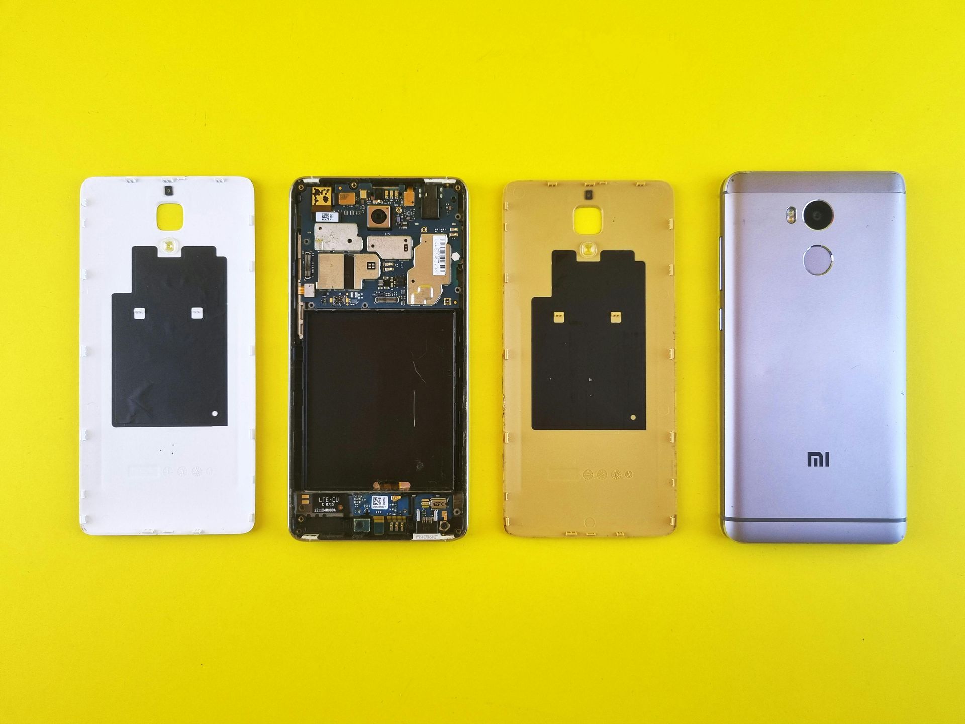 Four disassembled cell phone components, showcasing different states: back covers and internal components.