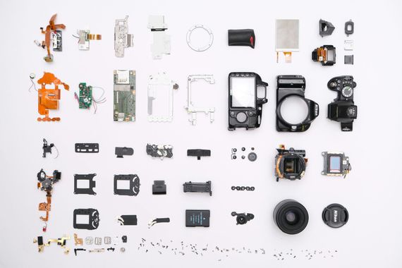 Disassembled camera parts laid out on a white surface, showcasing the components.